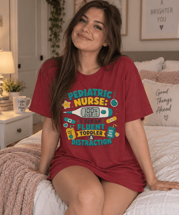 Pediatric Nurse Shirt with I Speak Fluent Toddler and Distraction lettering, thermometer and juice box design, front view