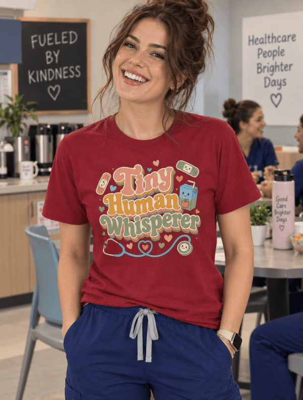Pediatric Nurse Shirt with Tiny Human Whisperer design, bandages, juice box and stethoscope, front view